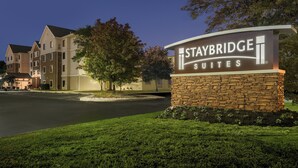 Een hotelschild voor Staybridge Suites, met een stenen basis en verlichte letters.