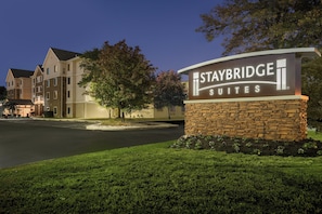 A hotel sign for Staybridge Suites with a stone base and illuminated lettering.