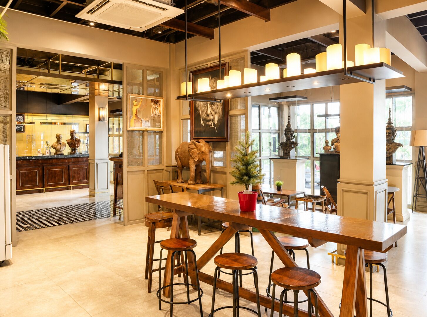 Zona de bar con barra de madera, taburetes y una escultura decorativa de elefante.