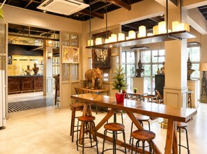 Zona de bar con barra de madera, taburetes y una escultura decorativa de elefante.