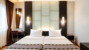 Een hotelkamer met een tweepersoonsbed, twee nachtkastjes, een bureau en een stoel.