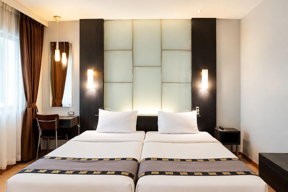 A hotel room with a double bed, two bedside tables, a desk, and a chair.