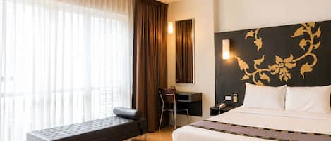 Una habitación de hotel con cama, escritorio, silla y banca.