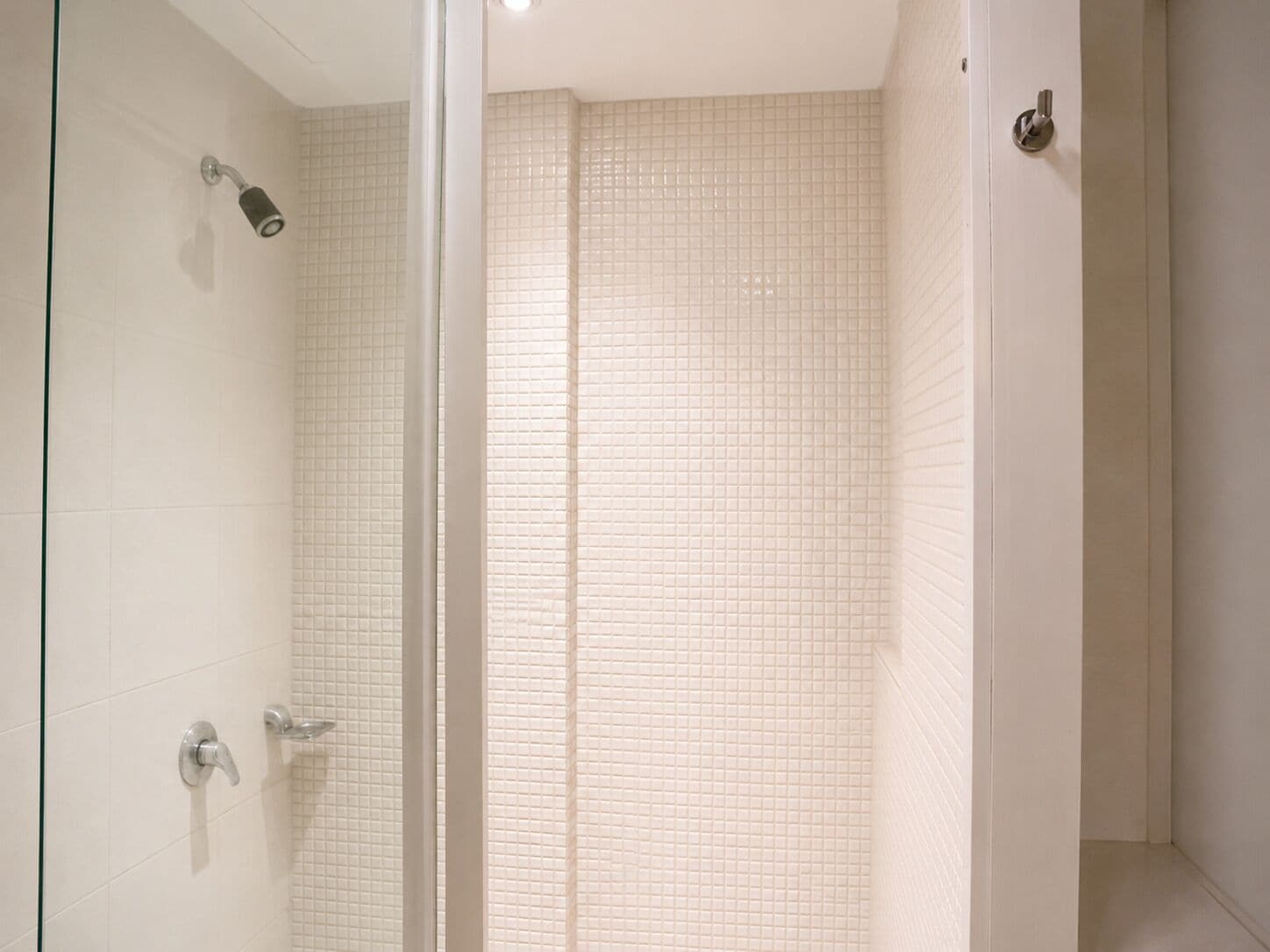 Ein Badezimmer mit Dusche, gefliesten Wänden und einer Glasabtrennung.