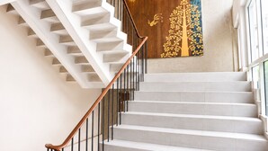 A staircase with a wooden handrail and white steps, leading to a landing with a decorative wall. - Swana Bangkok Hotel (Bangkok)