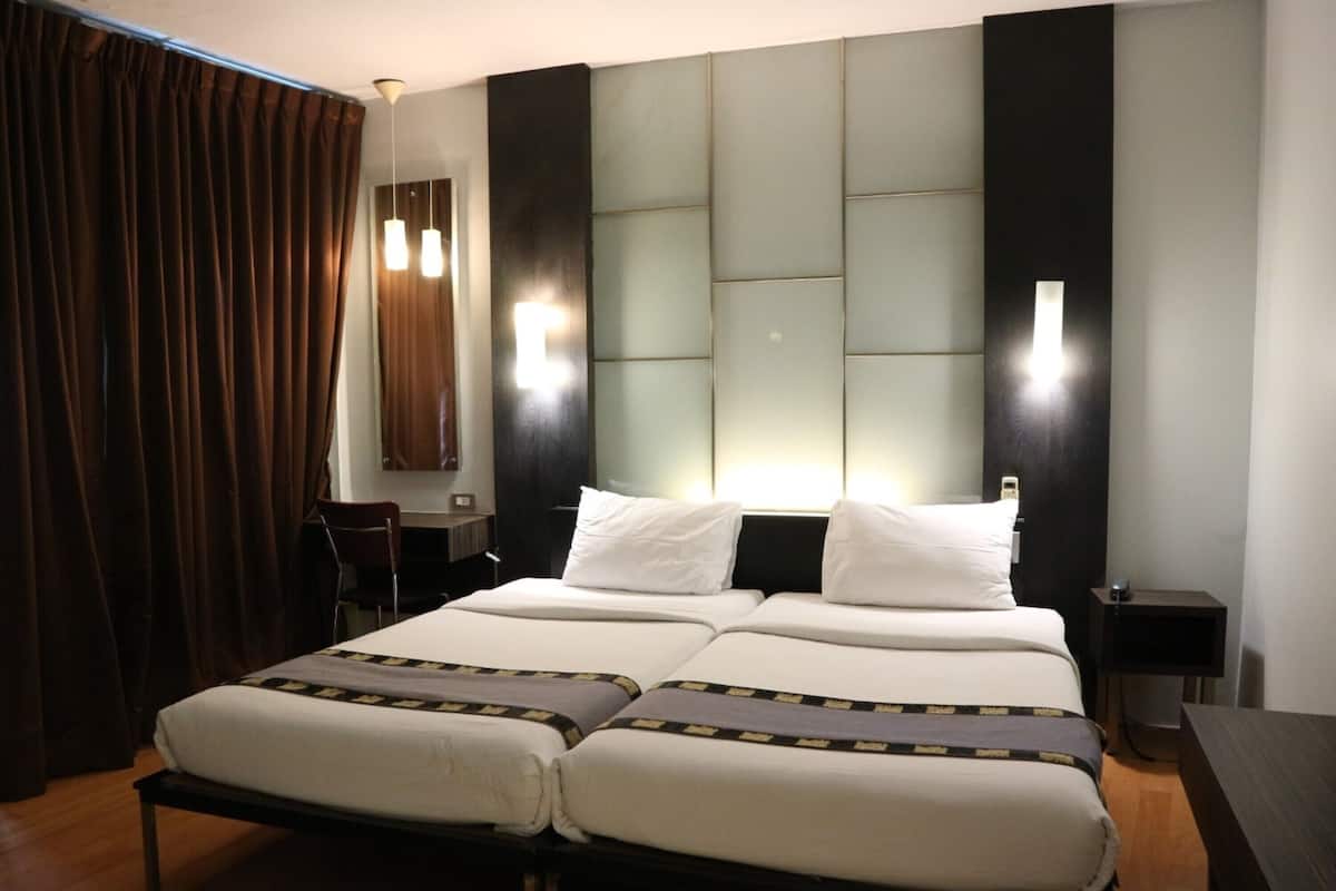 Uma cama de casal com cabeceira, mesas de cabeceira e uma escrivaninha com cadeira.