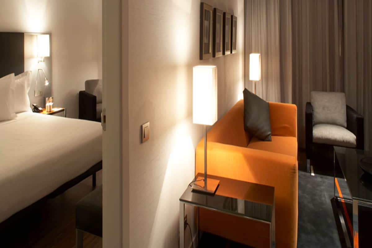 Une chambre d’hôtel avec un lit, un canapé, une chaise et un bureau avec une lampe.