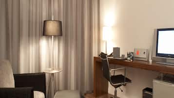 A hotel room with a desk, chair, lamp, and a television.