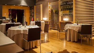 A restaurant with round tables, chairs, and a wooden floor.