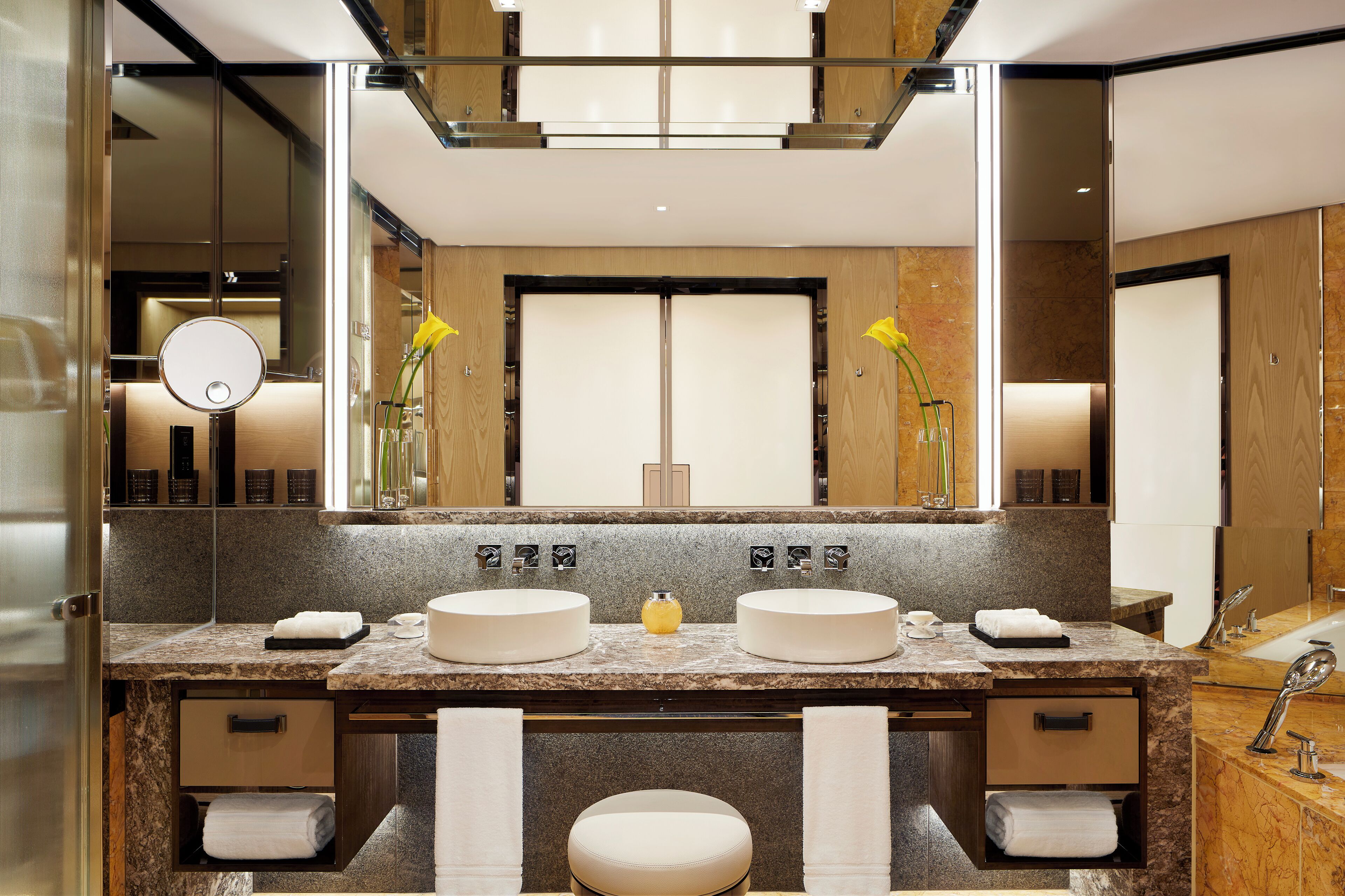 A modern bathroom with two sinks, a large mirror, and a vanity with storage drawers.