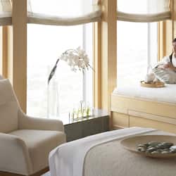 Relax in a serene space with a comfortable seating area, plush chair, and a neatly made bed.