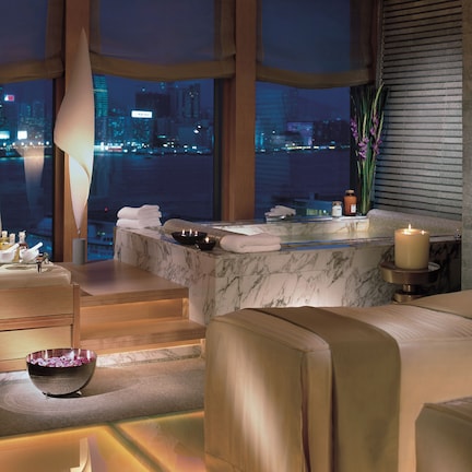 A spa room with a city view, a massage table, a bathtub, and a large bowl.