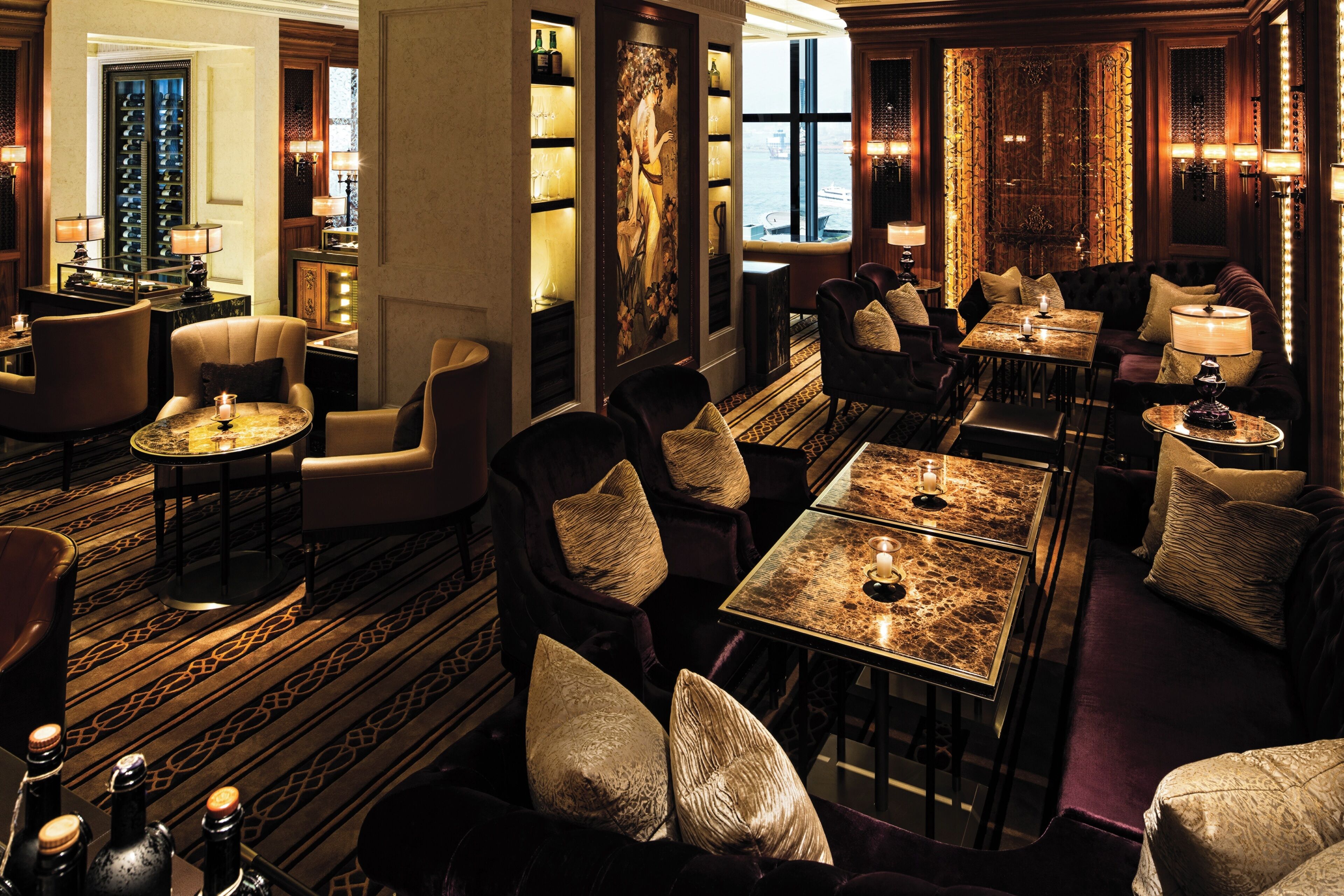 A luxurious hotel lobby with a bar, seating areas, and a large window offering a view.