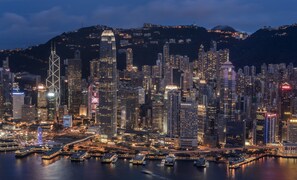 A nighttime cityscape with high-rise buildings, a prominent Ferris wheel, and a waterfront area with boats. - Four Seasons Hotel Hong Kong (Hong Kong)