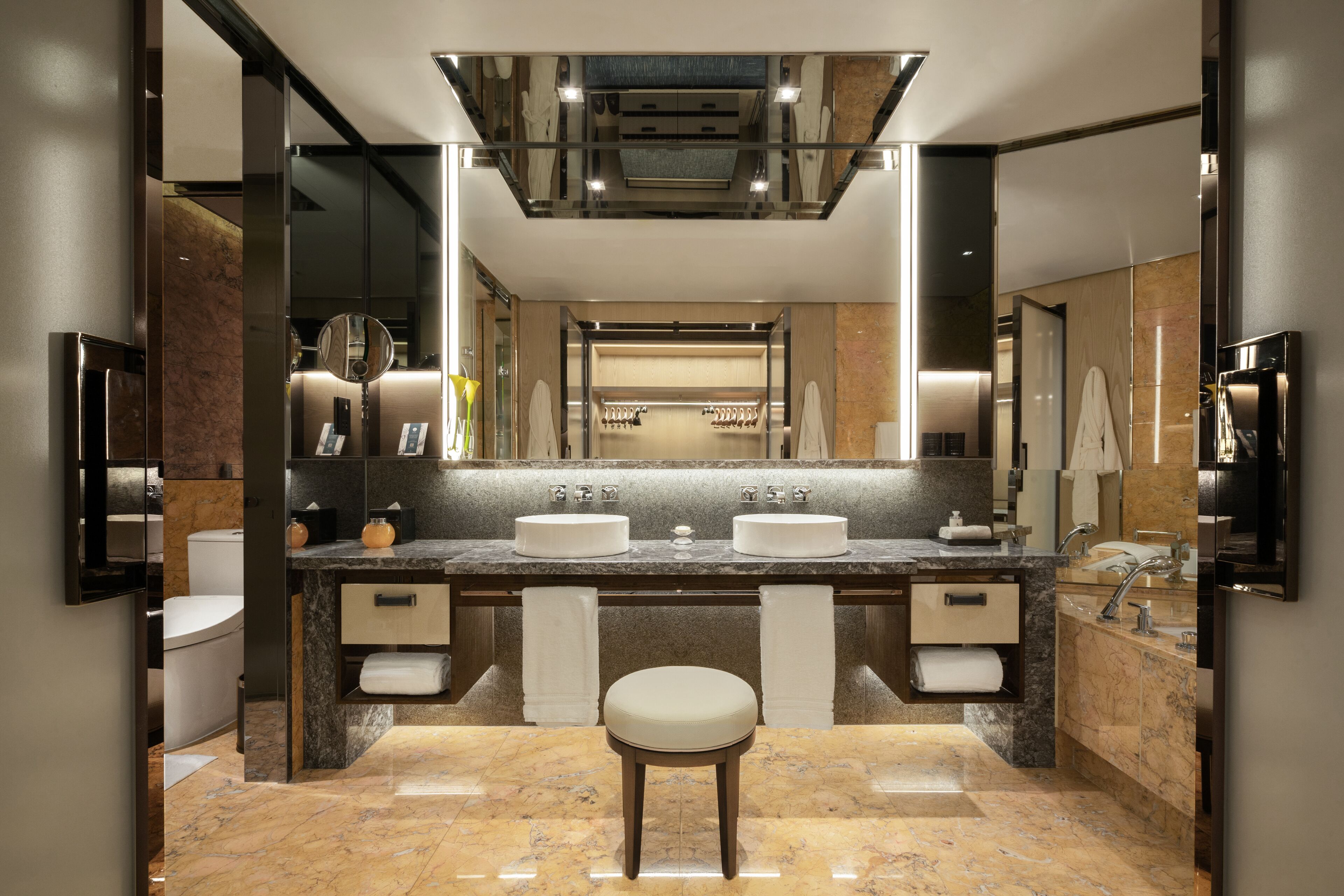 A modern bathroom with two sinks, a vanity, and a large mirror.