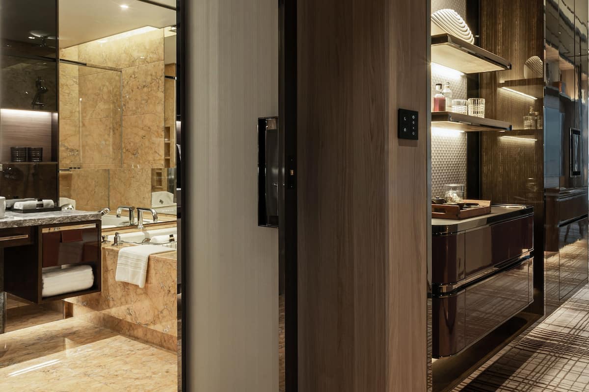Een moderne badkamer met een marmeren vloer, een grote spiegel en een houten wastafelmeubel.