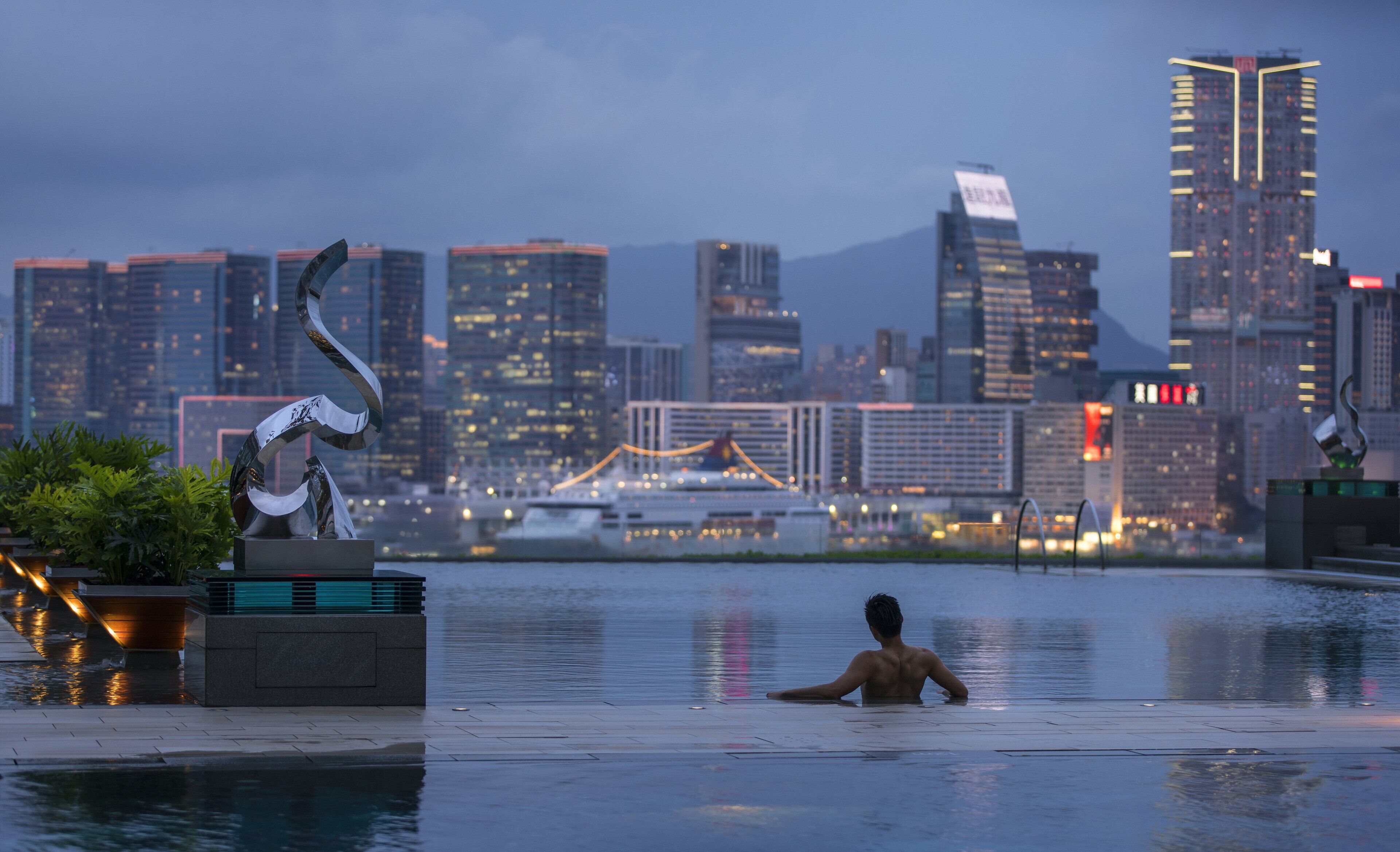 A man in a swimming pool with a cityscape in the background.
