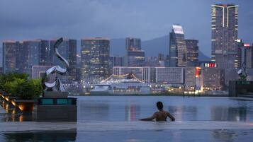 A man in a swimming pool with a cityscape in the background.