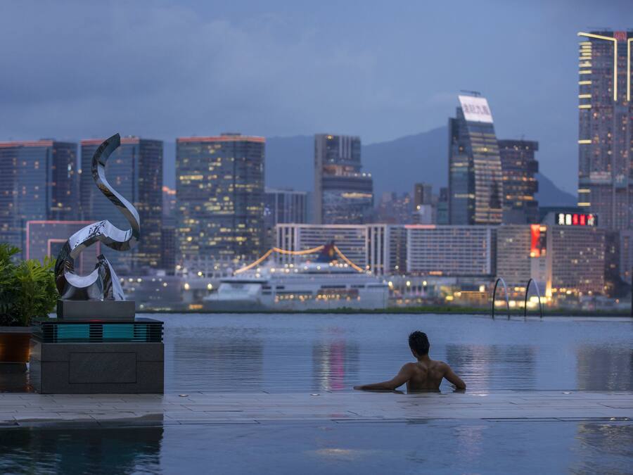 A man in a swimming pool with a cityscape in the background.