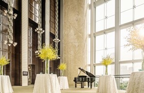 A grand hall with a grand piano, tall windows, and elegant chandeliers.