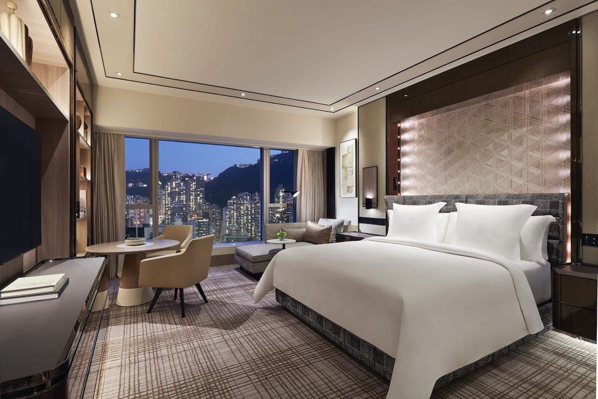 Een moderne hotelkamer met een groot bed, een zithoek, een bureau en uitzicht op de stad.