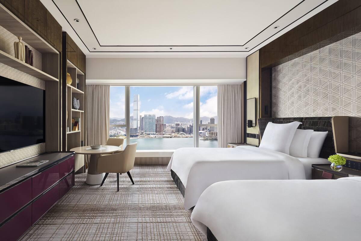 Hotelkamer met een groot bed, een televisie, een eettafel en uitzicht op een stadslandschap.