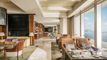 A spacious hotel lobby with a dining area, a bar, and a view of the sea.