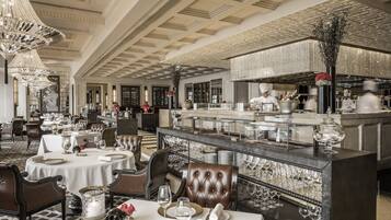 A luxurious dining area with round tables, leather chairs, and a central bar area.