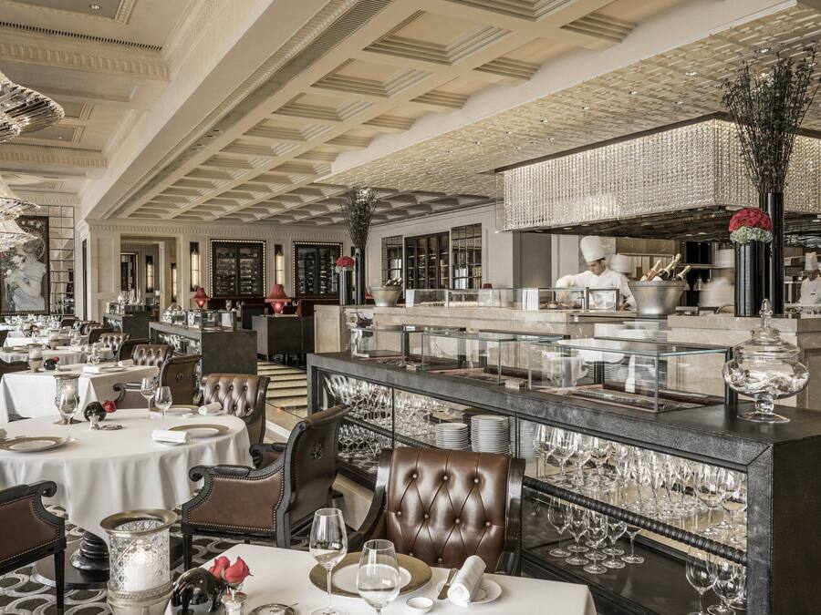 A luxurious dining area with round tables, leather chairs, and a central bar area.