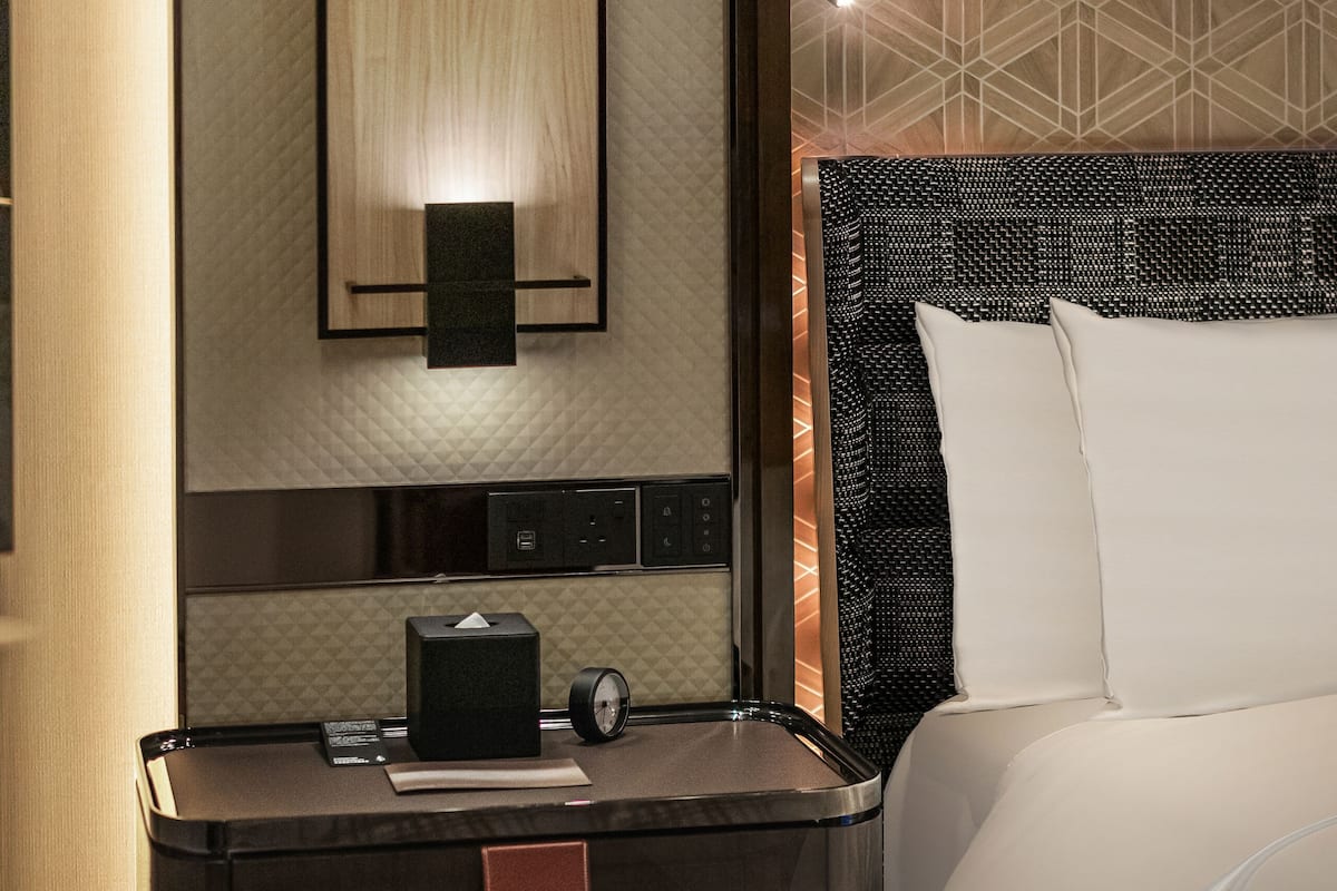 Hotelkamer met een bed, nachtkastje, wandlamp en een behang met patroon.