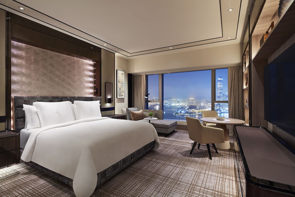 Een moderne hotelkamer met een groot bed, een zithoek en uitzicht op de stad.