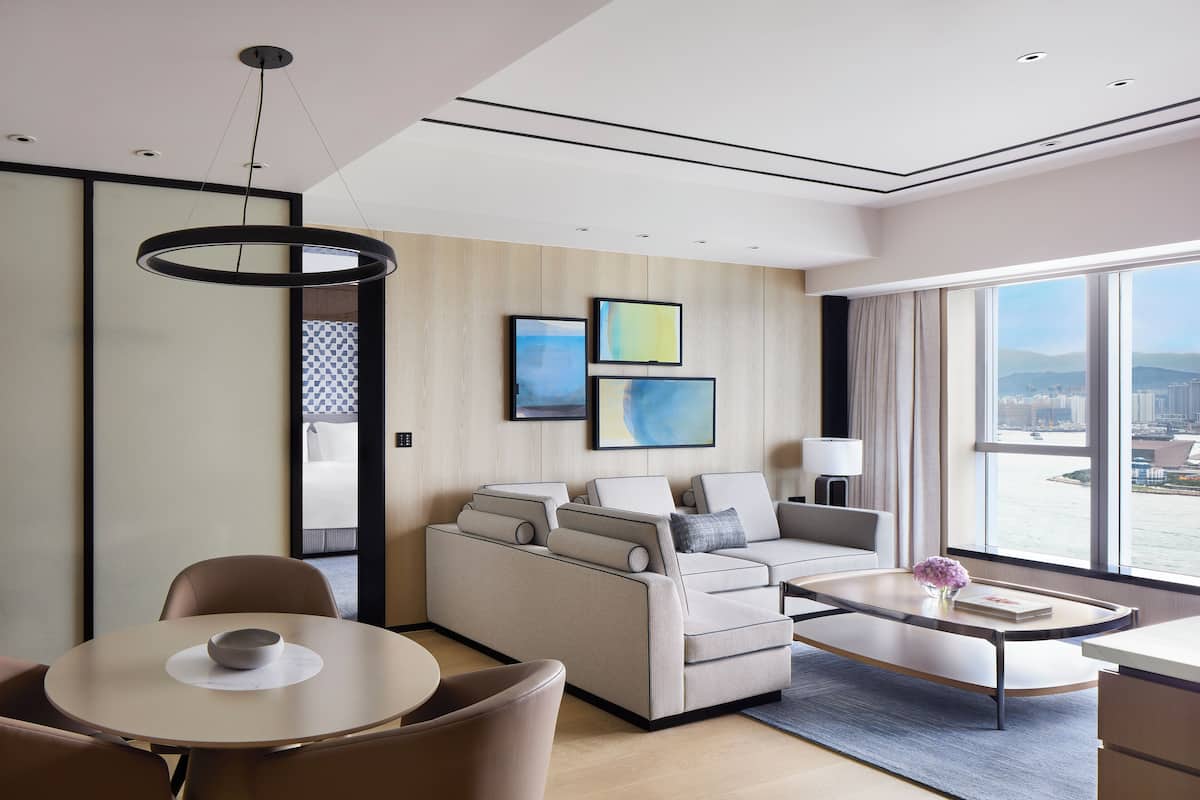 Een moderne hotelkamer met een bank, een eettafel en uitzicht op de stad.