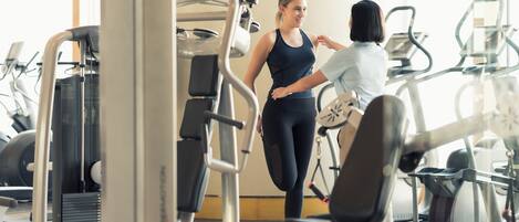 Un gimnasio con diversas máquinas de ejercicio, incluyendo cintas de correr y máquinas de pesas.