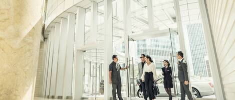 A modern building entrance with a glass facade, a marble column, and a clear view of the street outside.