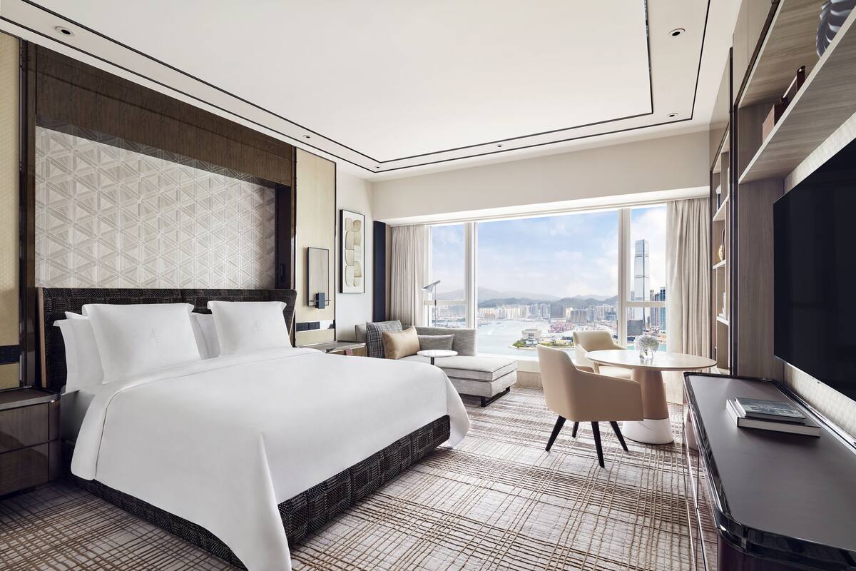 Een moderne hotelkamer met een groot bed, een bank, een ronde tafel en een televisie.