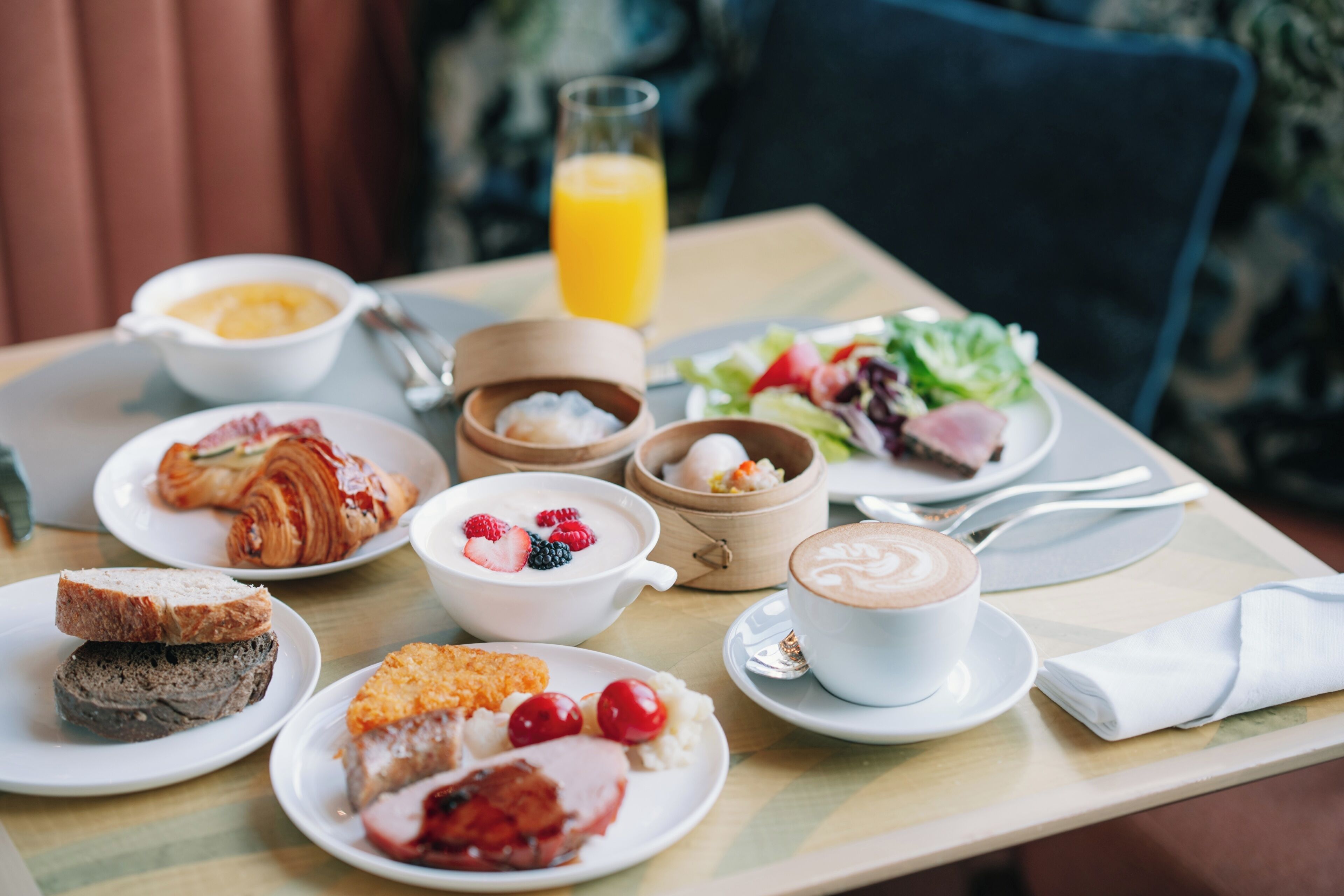 A breakfast setting with croissants, fruit, yogurt, and coffee on a table.