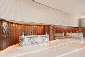 A modern hotel lobby with marble reception desks and wooden paneling.