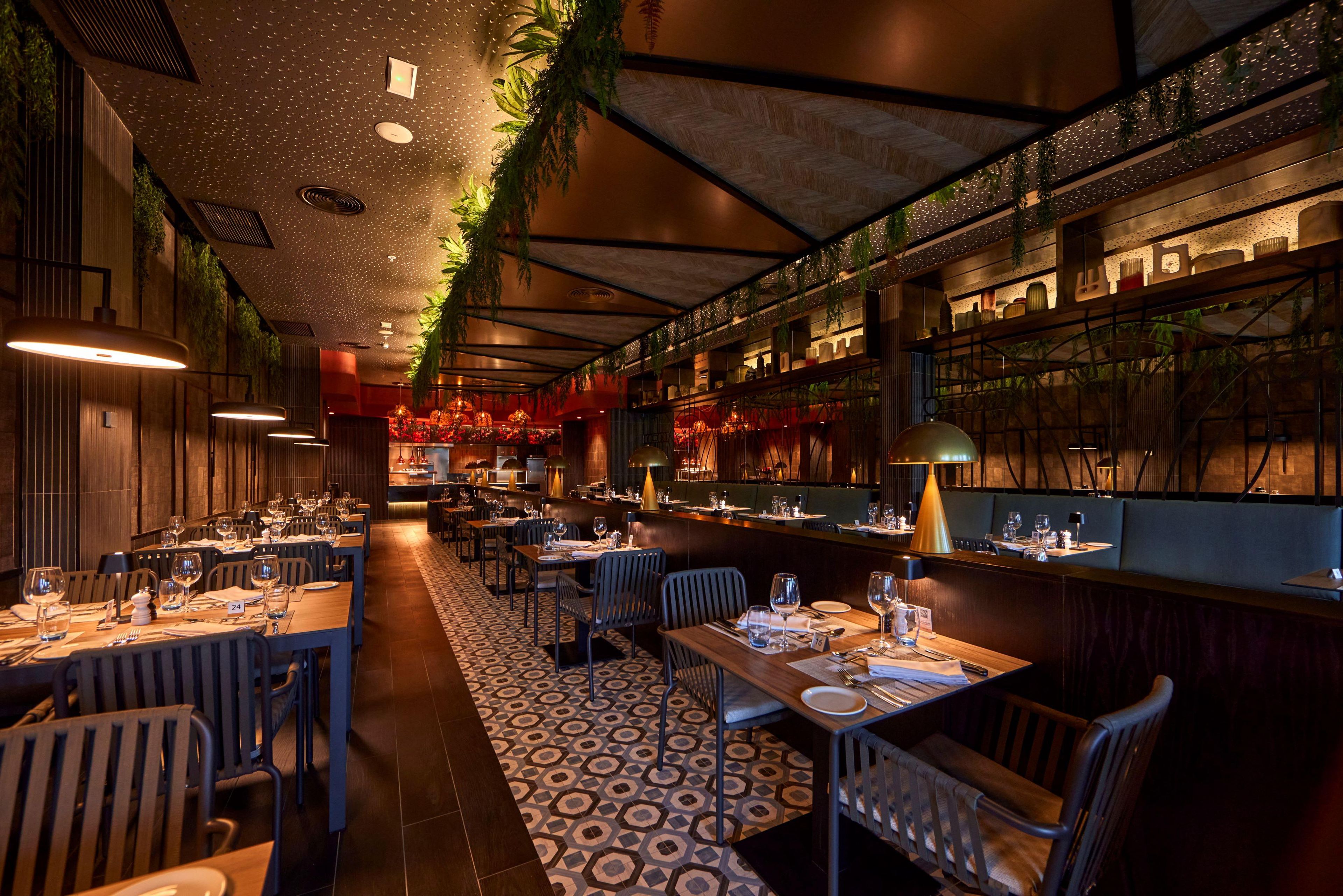 Een restaurant met meerdere eettafels, stoelen en een vloer met een patroon.