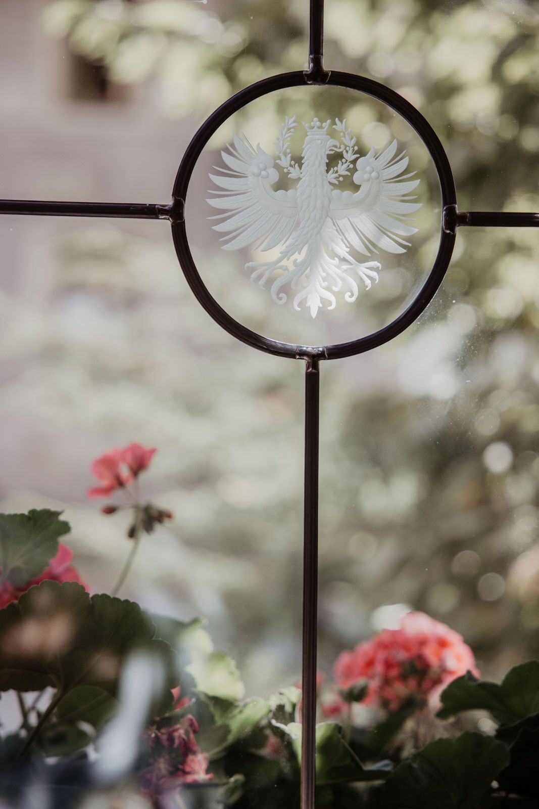 A window with a decorative metal grille featuring a white embossed design.