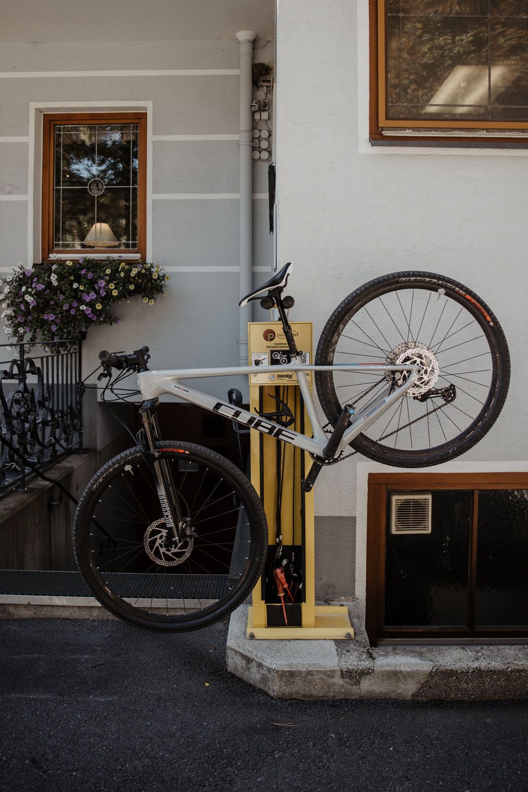 Un vélo est fixé sur un support à vélos mural, devant un immeuble.