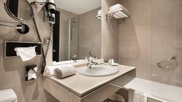 A modern bathroom with a sink, mirror, towel rack, and a shower area.