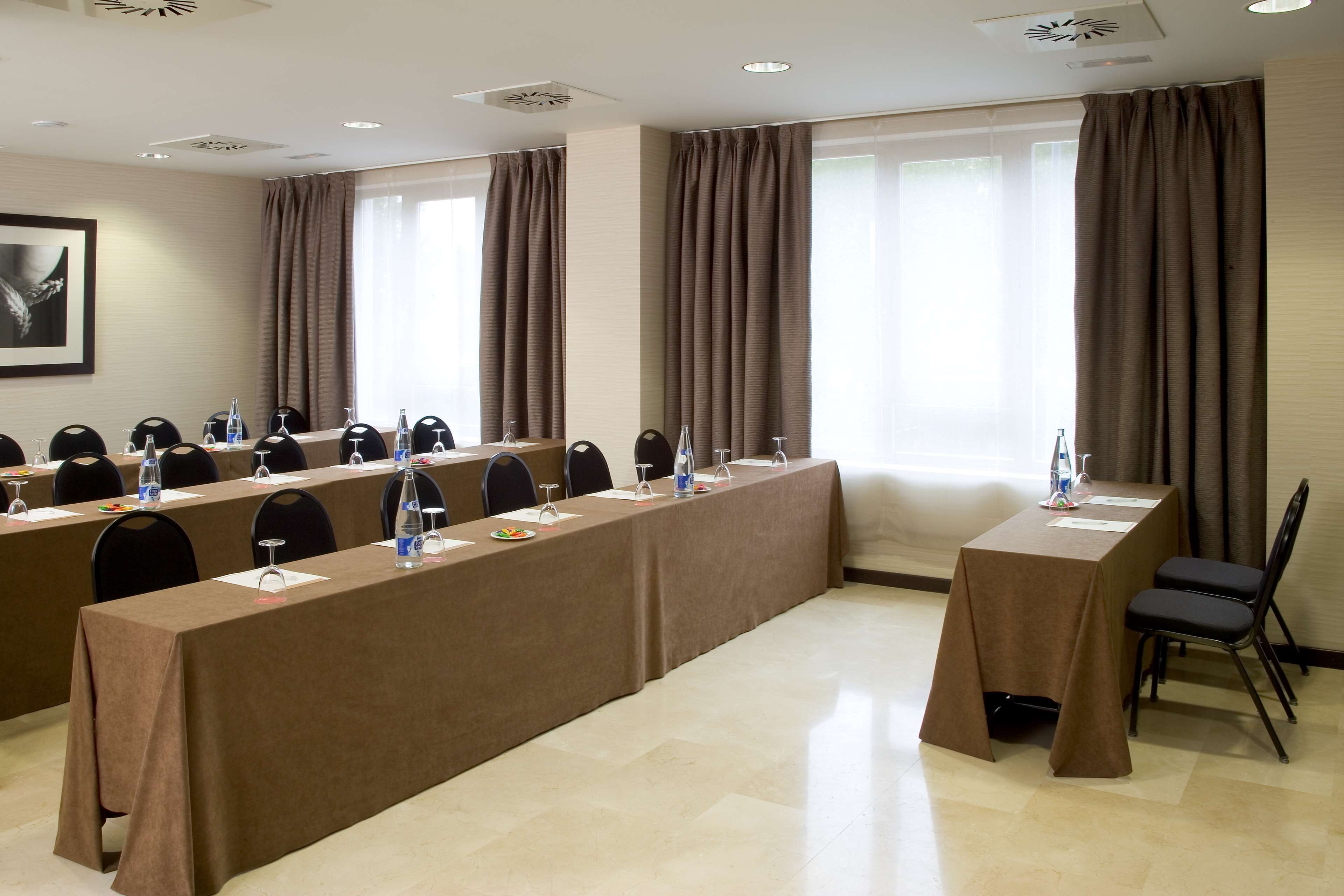 Un salón de conferencias con una larga mesa, sillas y una pequeña mesa con un sillón.