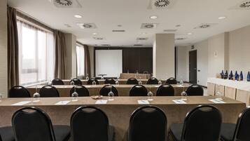 A conference room with a long table, chairs, and a projector screen.