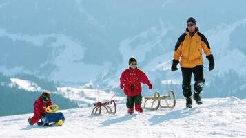 A snowy landscape with a person in a yellow jacket and a child in a red jacket.