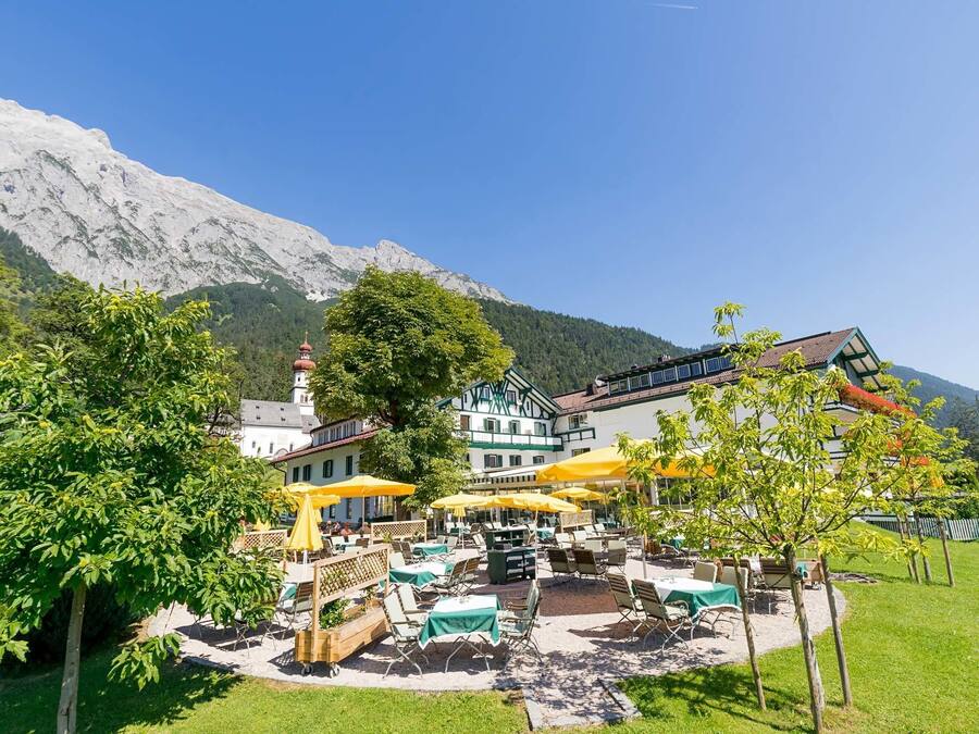 Een hotel met terras en een berg op de achtergrond.