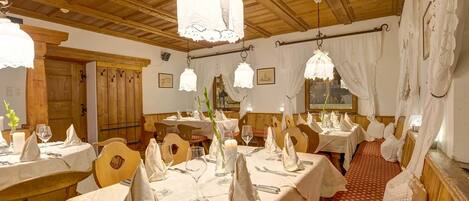 A restaurant with wooden ceilings and tables set for dining.