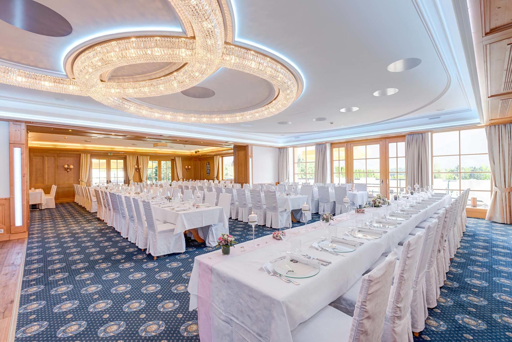 A banquet hall with round tables, white tablecloths, and chairs.