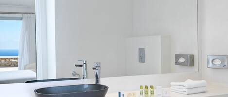 Ein modernes Badezimmer mit einem großen Spiegel, einem schwarzen Händewaschbecken und einer weißen Arbeitsplatte.