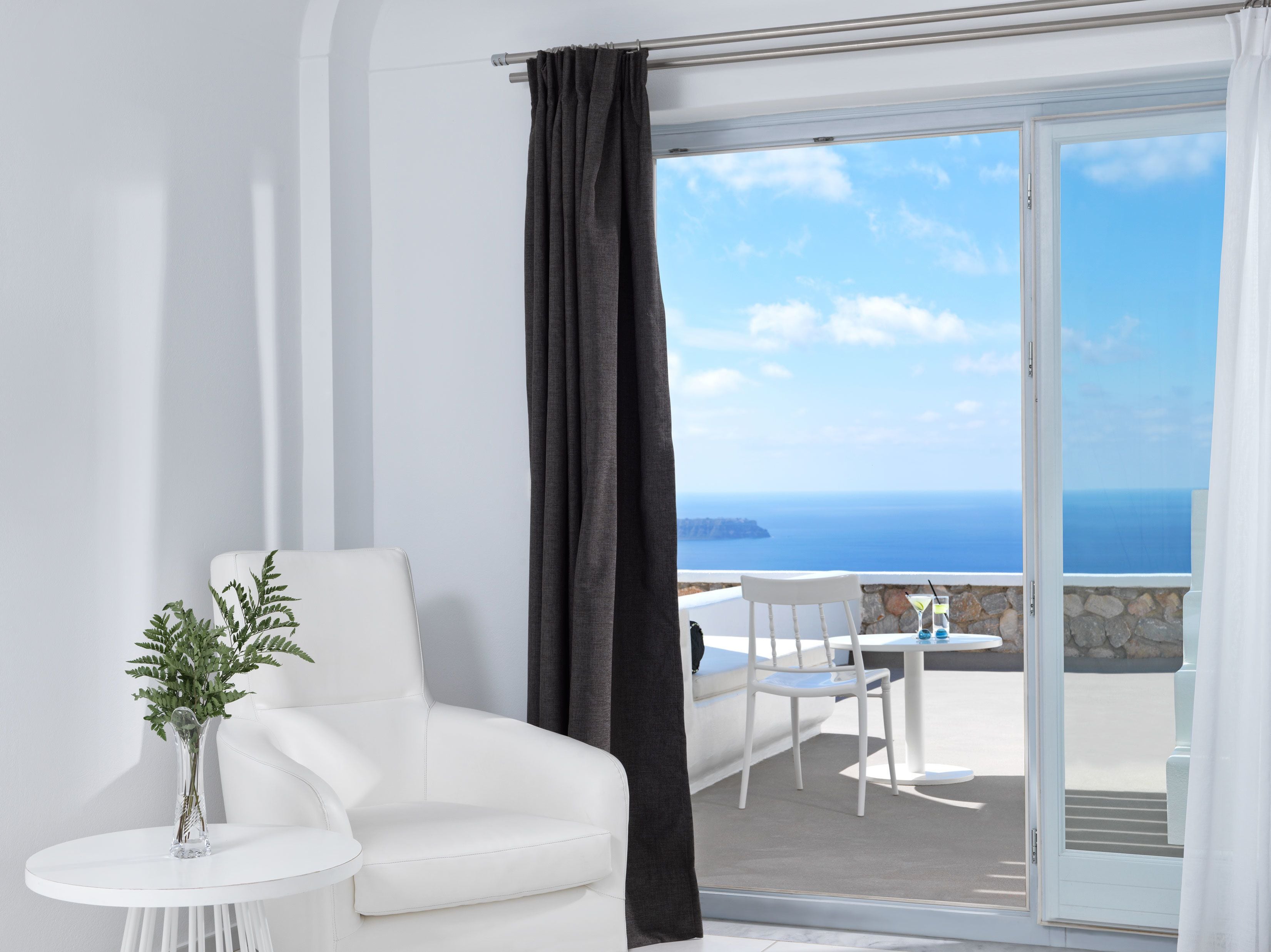 Una silla y una mesa blancas en un balcón con vistas al mar.