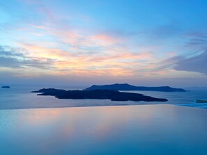 Escena costera tranquila con cielo despejado y mar en calma, con islas distantes y superficie acuática reflectante.